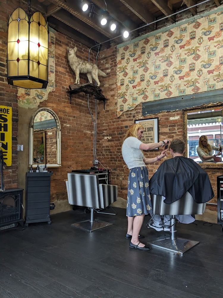 Stylist cutting a client's hair inside the brick-walled salon